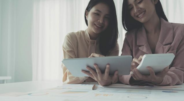 Asian Young colleague business presents and explains and using laptop computer in an office. Teamwork, coworker cooperation, financial marketing team, or corporate business employee concept..