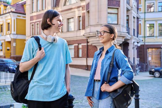 Teenage friends male and female talking on street of city. Fashionable having fun teenagers guy and girl together outdoor. Friendship, communication, holidays, lifestyle, youth, urban style
