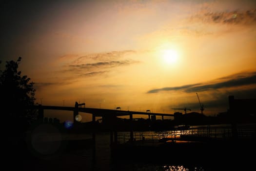 silhouette of skyline,river and bridge during sunset.