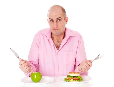 Caucasian man undecided if he is gonna go for the apple or for the hamburger, isolated on white background.