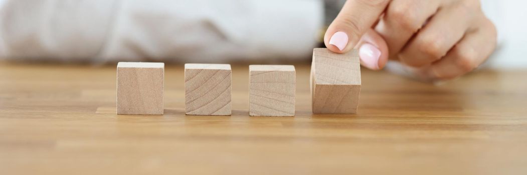 Close-up of business woman flipping one wooden cube from row. Change situation, positive thinking. Success, strategy, solution, progress, business concept