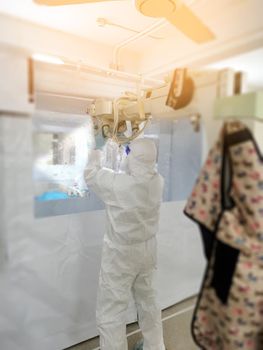 The technician in coverall using X-ray machine portable for examining patient coronavirus during global pandemic. Medical team wearing protective suit PPE.