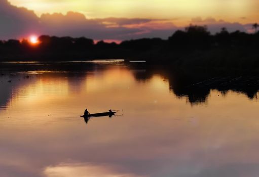 Silhouette of Thai fisherman on wooden boat .