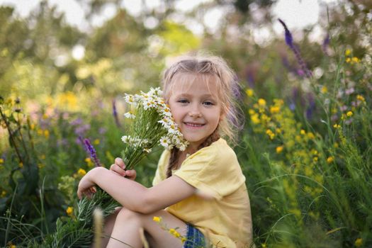 Girl with a bouquet of daisies sits in a forest