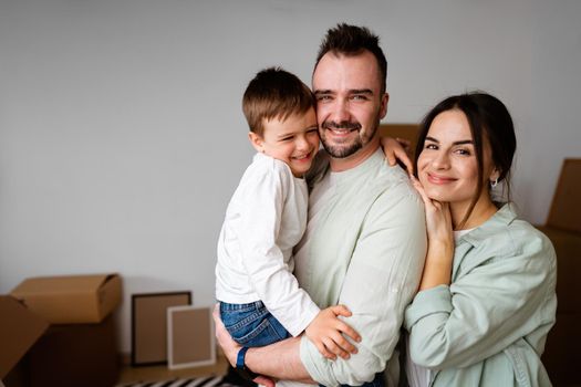 Young parents and son having fun during moving day to new house, portrait