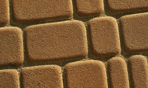 a wide way leading from one place to another, especially one with a specially prepared surface which vehicles can use. Yellow brown brick road.Cobblestones on the pavement close-up.