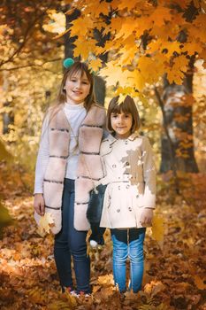 Children in the park with autumn leaves. Selective focus.