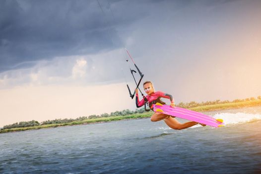 A young woman kitesurfer rides the waves doing a trick. Marine sports. kitesurfing.