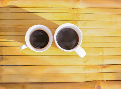 Two cups of coffee on wooden background .
