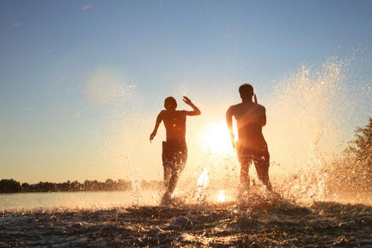 Group of young people playing games on sandy beach on a summer day.