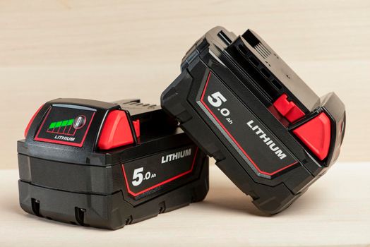 Lithium battery for cordless drill. Screwdriver battery. Four batteries with a charge indicator lie on a wooden background.