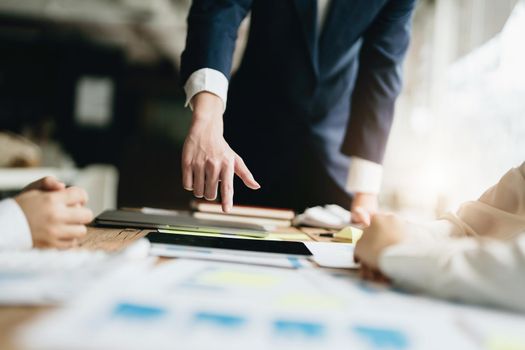 Male businessman pointing to documents summarizing marketing strategy with female colleagues in meeting, teamwork, investment planning.