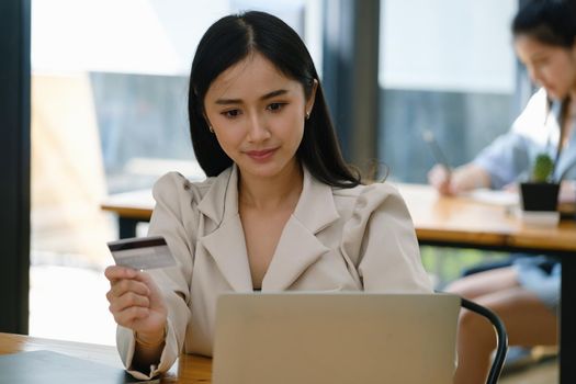 Online Shopping and Internet Payments, Beautiful Asian women are using their credit cards and computer laptop to shop online or conduct errands in the digital world.