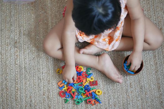 child girl playing with colorful plastic letters .