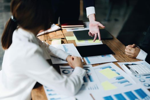 Male businessman pointing to documents summarizing marketing strategy with female colleagues in meeting, teamwork, investment planning.