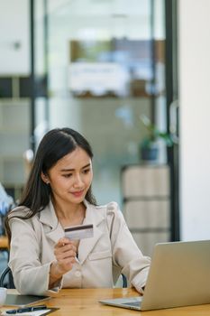 Online Shopping and Internet Payments, Beautiful Asian women are using their credit cards and computer laptop to shop online or conduct errands in the digital world.