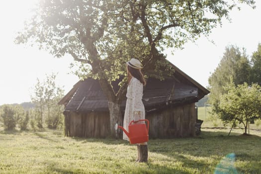 Young female gardener watering the plants in the garden in summer. Young woman with a watering can.