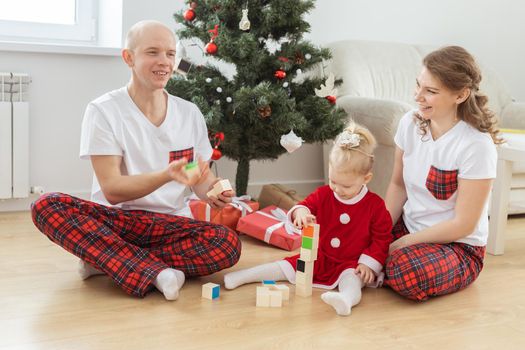 Baby child with hearing aid and cochlear implant having fun with parents in christmas room. Deaf and health