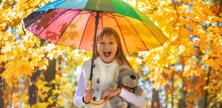 Child under an umbrella in the autumn park. Selective focus.