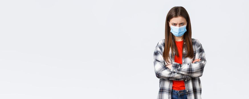 Coronavirus outbreak, leisure on quarantine, social distancing and emotions concept. Angry young mad girlfriend in medical mask and checked casual shirt, feel offended, sulking and stand defensive.
