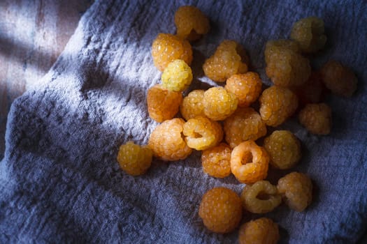 Yellow raspberry on blue cloth, extreme close up, copy space, selective focus, top view.