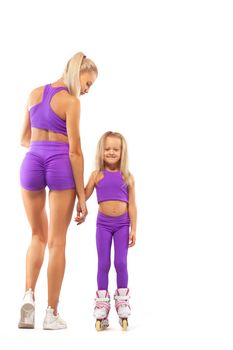 Good looking family, mother and daughter, posing in studio wearing inline roller skates.