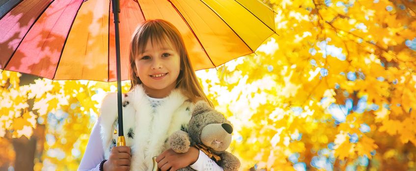 Child under an umbrella in the autumn park. Selective focus.