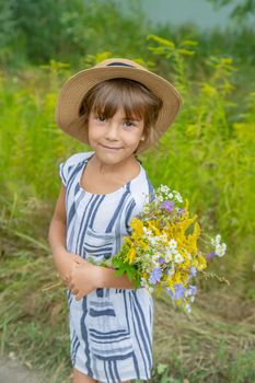 girl holding wildflowers in the hands of a child. Selective focus.