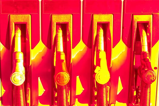 Red neon pistols for refueling cars with diesel or gasoline. A filling station is a facility that sells fuel and engine lubricants for motor vehicles.