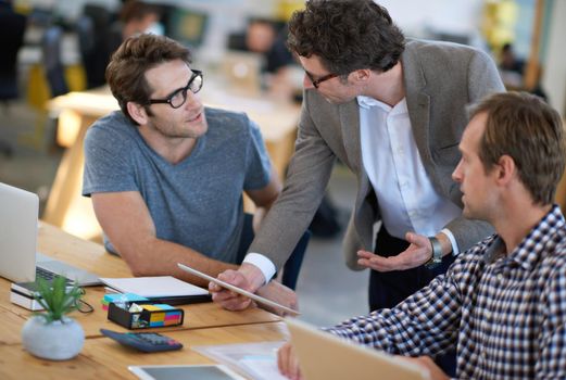 Shot of business colleagues discussing matters with the help of wireless technology in their office.