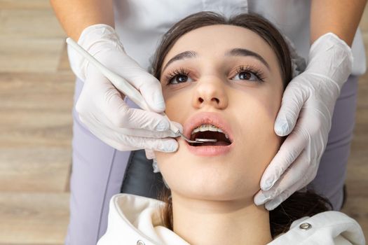 Dentist examining patient teeth with mirror in dentist clinic. Having dental checkup