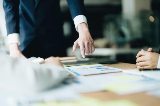 Male businessman pointing to documents summarizing marketing strategy with female colleagues in meeting, teamwork, investment planning.