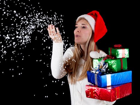 Winter woman with gifts blowing christmas snow from hands, isolated on black.