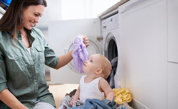 Shot of a mother and her baby girl playing while doing laundry.