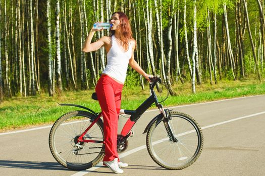 young woman on the bicycle drinking water