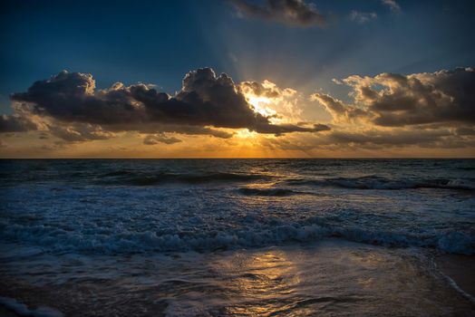 Sunset on the Caribbean Sea. The sun's rays make their way through the clouds.