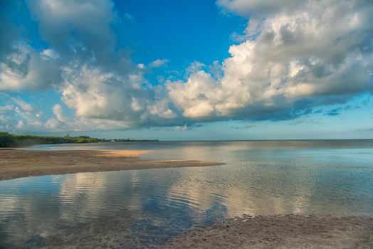 The sky with clouds reflected in the waters of the estuary. Sunny weather.