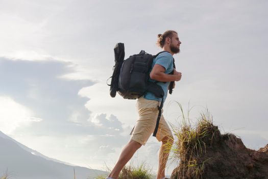 Hiker man with backpack travel on top volcano Batur, Indonesia