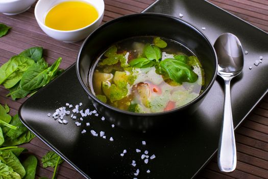 Tuscan vegetable soup with basil pesto in black plate