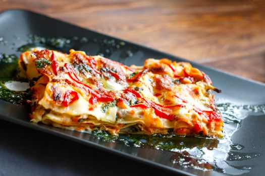 traditional italian lasagna with minced beef bolognese sauce, black modern plate, top view