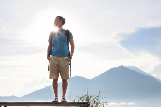 Hiker man with backpack travel on top volcano Batur, Indonesia