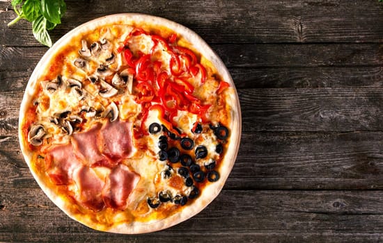 Assorted 4 parts Delicious fresh Pizza with bacon, mushrooms, peppers and olives on the wooden background. Top view.