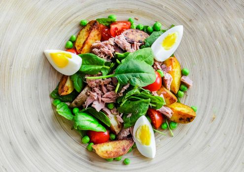 Tuna salad with lettuce, eggs and tomatoes on wooden plate