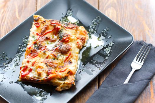 traditional italian lasagna with minced beef bolognese sauce, black modern plate, top view