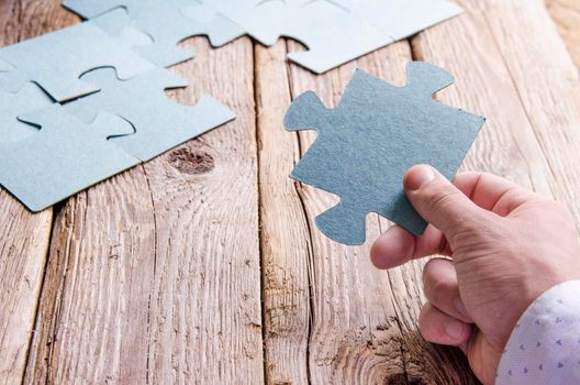 Incomplete puzzles lying on wooden rustic boards. Conceptual of innovation, solution finding and integration. Hand with puzzle piece