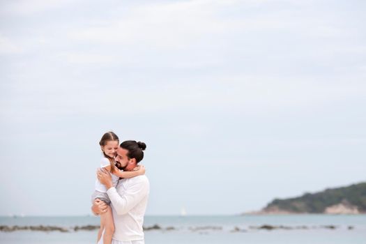 Father and daughter holding hands and walking on deserted tropical beach together happy and loving vacation