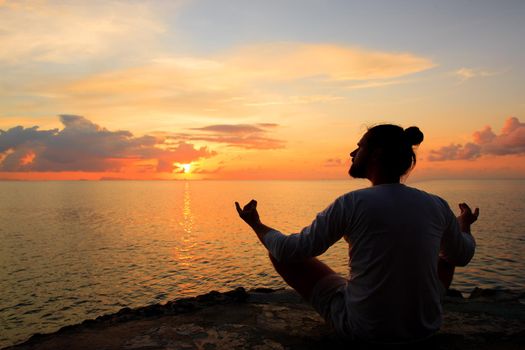 Yoga scene man silhouette in sunset background.