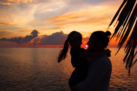 Silhouette of father and daughter on the beach at dusk. Sunset