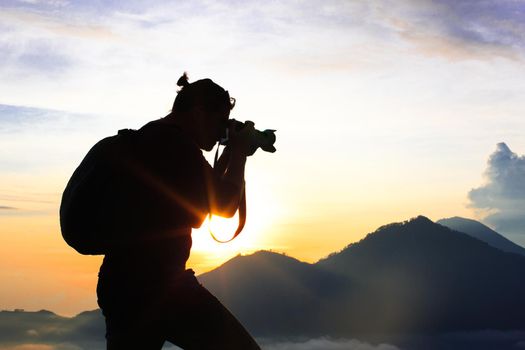 Photographer Hiker walking along, takes pictures and meets sunrise on the mountain