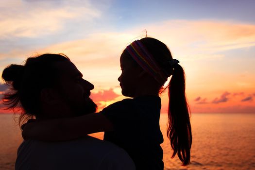 Silhouette of father and daughter on the beach at dusk. Sunset